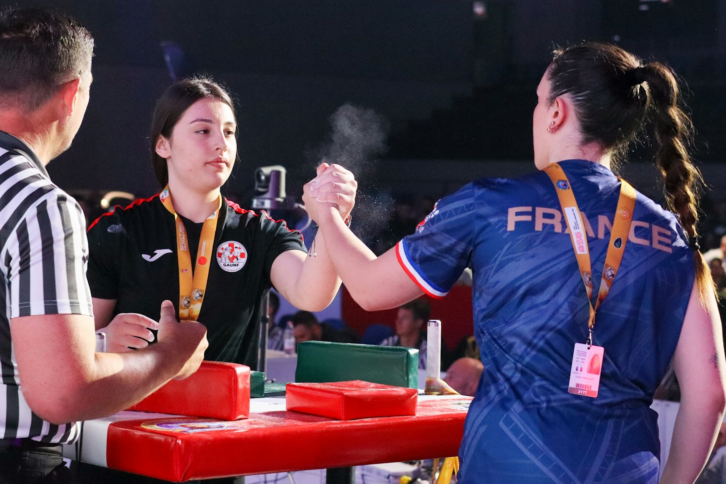 Due donne lottano per il braccio mentre un arbitro osserva la partita.